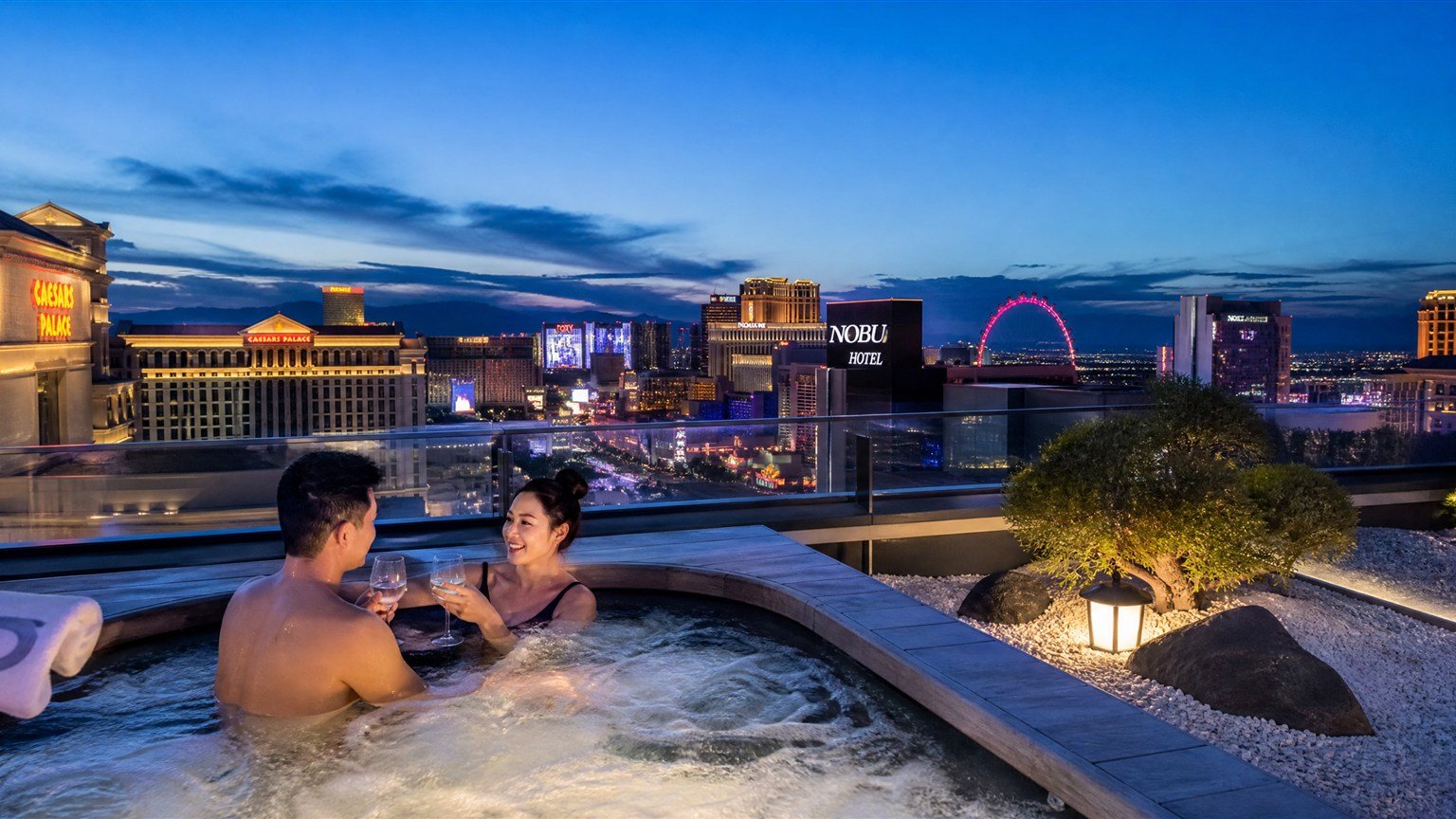 Couple in a rooftop whirlpool at the Nobu Villa at Caesars Palace with the Las Vegas Strip behind them