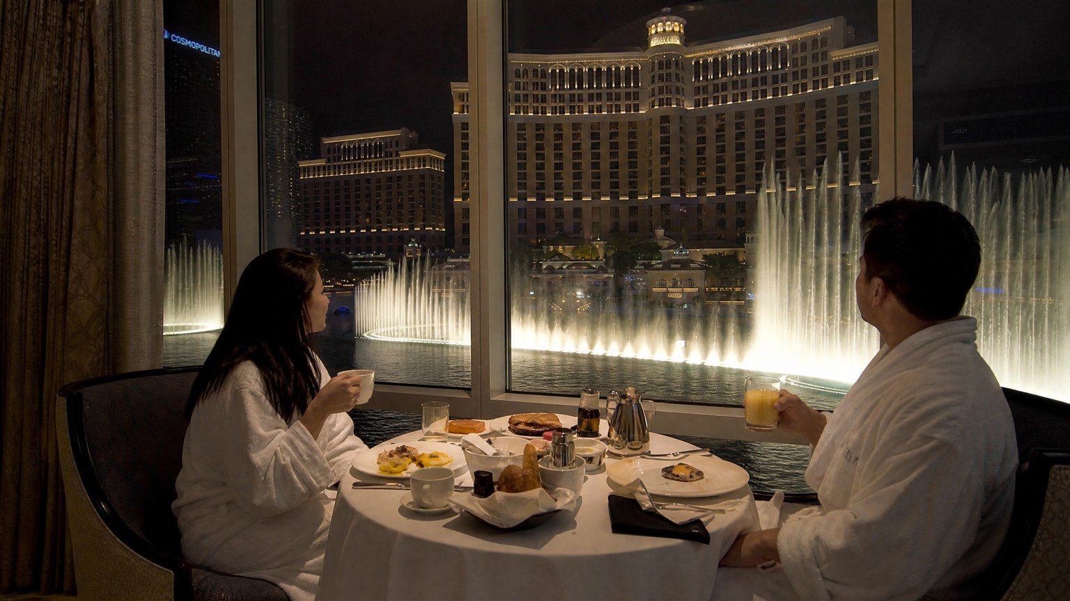 Couple watching the Bellagio fountains from a Lakeview suite in Las Vegas